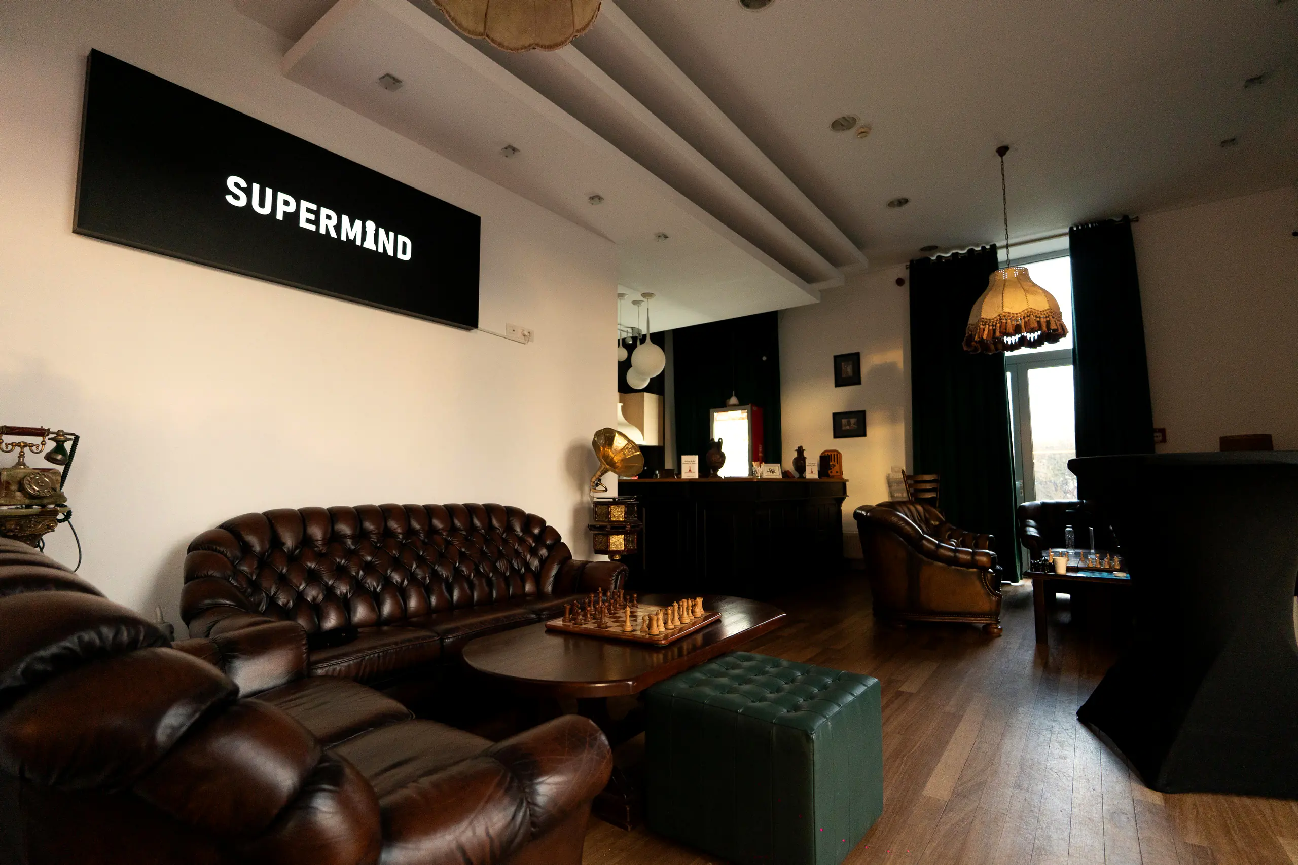 Salonul clubului Supermind: canapele Chesterfield, perete de cărți și sigla luminoasă