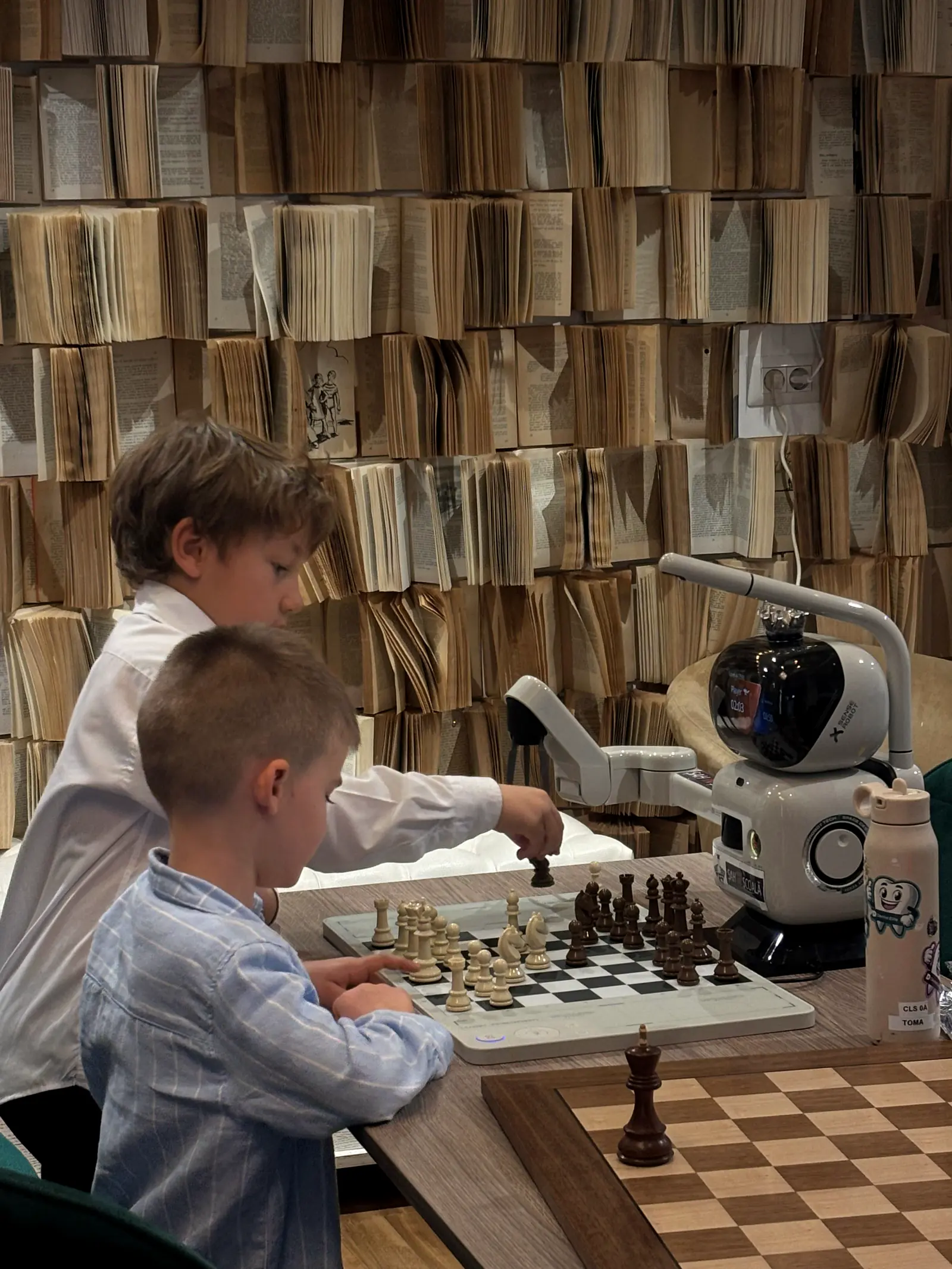 Copil jucând o partidă împotriva robotului de șah al clubului